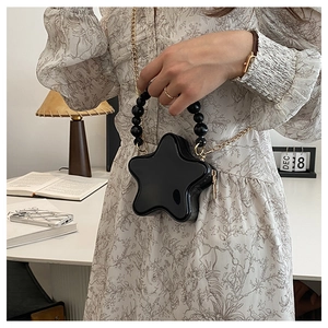 Close-up of star-shaped patent leather purse with black beaded handle and gold chain detail