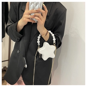 Detail of white star-shaped mini crossbody bag with pearl handle and gold chain strap