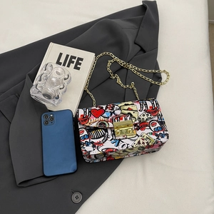 Graffiti print flap crossbody bag with gold chain strap on grey blazer background
