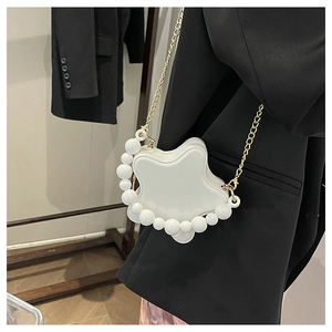 Detail of star-shaped white bag featuring glossy finish and elegant pearl handle