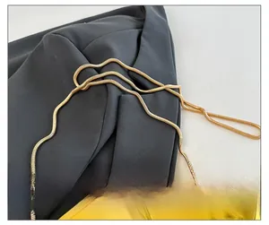 Détail de la bandoulière en chaîne dorée et de la surface polie du sac en acrylique