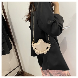 Detailed view of cream star-shaped crossbody bag featuring decorative pearls and gold chain