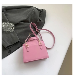 Pink house-shaped leather tote bag with gold hardware shown on a white tabletop