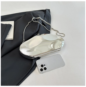 Sac de soirée en acrylique miroir argenté avec chaîne serpent près d'un téléphone