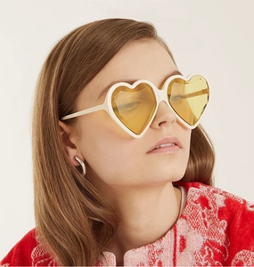 Nahaufnahme einer weißen Herz-Sonnenbrille mit gelben Gläsern an einem Model