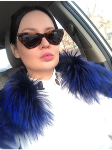 Close-up of tortoise shell cat-eye sunglasses with luxury logo detail and blue fur trim
