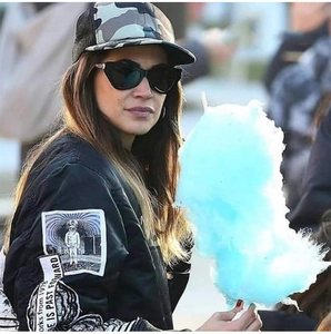 Close-up of retro black cat-eye sunglasses worn with a street style bomber jacket