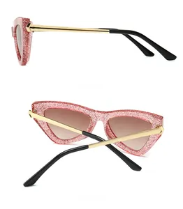 Detail of glittery pink cat-eye sunglasses with gold metal temples and gradient lenses