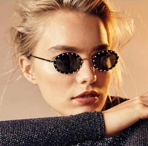 Close-up of vintage oval sunglasses featuring rhinestone-embellished frames and metal temples