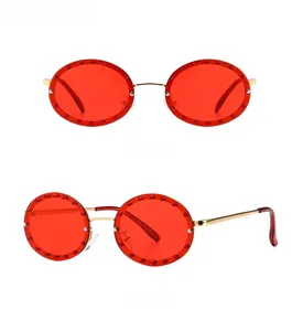 Detail view of round gold metal sunglasses featuring red lenses and rhinestone embellishments