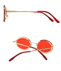 Detail view showing side and back of red round sunglasses with gold metal frame