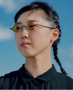 Steampunk round sunglasses with yellow lenses and black metal frames against a blue sky