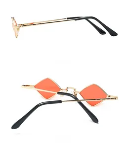 Detail of trendy gold metal sunglasses featuring orange diamond lenses and slim black earpieces
