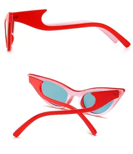 Detail view of red cat eye sunglasses with unique wavy temples and teal lenses