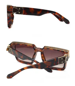 Détail de lunettes de soleil carrées en écaille avec charnières dorées et verres dégradés