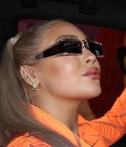 Close-up of model wearing transparent square sunglasses and silver drop earrings