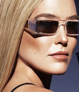 Close-up of stylish light pink square frame sunglasses with tinted lenses on a model