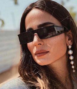 Close-up of elegant long gradient pearl earrings and vintage black rectangular sunglasses