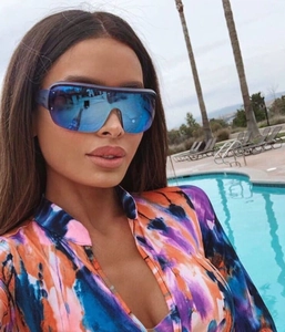 Outdoor model shot showing oversized blue shield sunglasses with one-piece wrap lens design