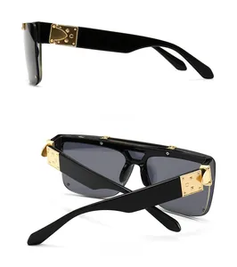 Detail view of large black frame sunglasses with wide gold metal hinge decorations