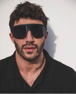 Close-up of matte black wrap-around sports sunglasses on male model with tinted lens