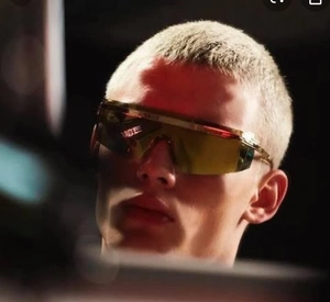 Macro side view of futuristic gold shield sunglasses with mirror lenses on model