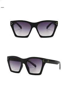 Detail of square black sunglasses featuring gold triple rivet accents and gradient lenses