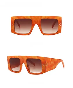 Close-up of orange tortoiseshell sunglasses with gradient brown lenses and silver rivets