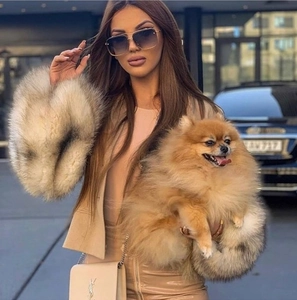 Close-up of beige leather chain bag with gold metal logo and luxury faux fur cuff jacket