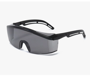 Close-up of safety goggles featuring black frames with hollow temples and grey lenses