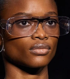 Vue macro de lunettes futuristes oversize avec monture claire et détail de pont noir