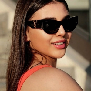 Detail einer schwarzen Cat-Eye-Sonnenbrille mit goldener V-Logo-Verzierung am Bügel