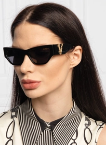 Nahaufnahme schwarzer Cat-Eye Sonnenbrille mit goldenem V-Logo und polarisierten Gläsern