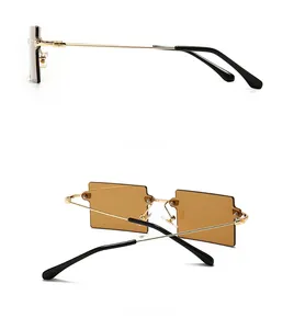 Detail view of rectangular rimless sunglasses with amber lenses and golden metal temples