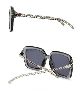 Detail view of square sunglasses featuring silver metal chain temples and grey lenses