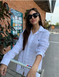 Detail of white cotton shirt with blue polo embroidery and black oversized sunglasses