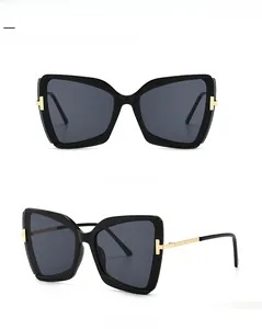 Detailansicht der Schmetterling-Sonnenbrille mit goldenen T-Metallakzenten am schwarzen Bügel