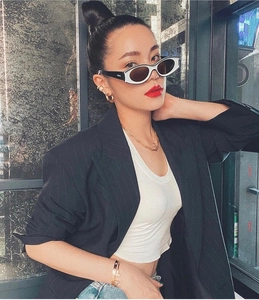 Close-up of black and white cat-eye sunglasses with gold chain necklace on a model