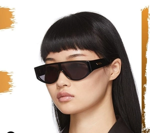 Detail of modern black oversized wrap sunglasses with decorative gold metal hinge accents