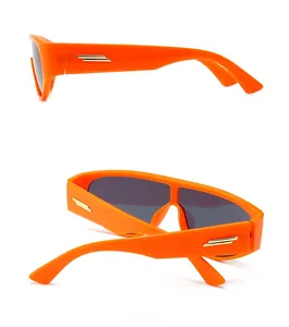 Detail view of modern orange sunglasses with signature gold metal bars on the temples