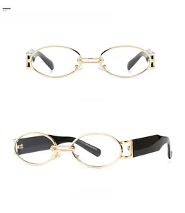 Close-up of golden oval metal sunglasses with bolt hinge and black temple detail