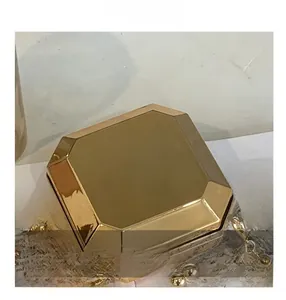 Detail of a gold octagonal geometric box bag with mirror finish and ball chain tassel
