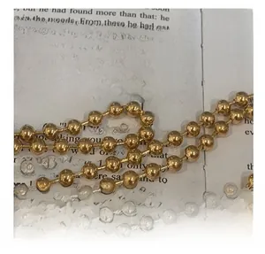Close-up of a glossy gold beaded metal chain strap resting on vintage book pages