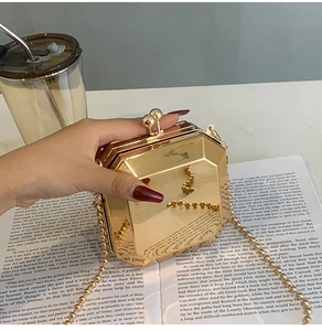 Close-up of golden octagonal metal box clutch bag with ball chain and ball lock design