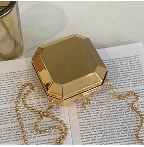 Detail of a geometric gold metal clutch bag with mirrored facets on a vintage book