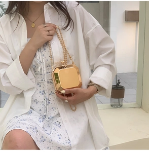 Detailed macro view of the glossy gold octagonal metal clutch with beaded handle strap