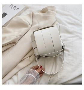 Close-up of white woven texture PU leather handbag with metallic chain and strap