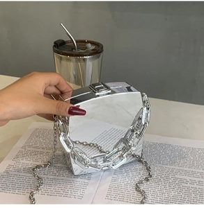 Detail of silver mirror acrylic box bag with thick chain strap and metal clasp