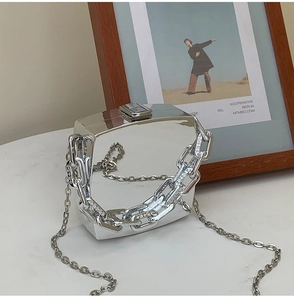 Macro shot of silver mirrored geometric clutch bag with thick chain and metal buckle