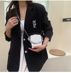 Silver mirror box bag with chunky chain detail worn by model in black blazer